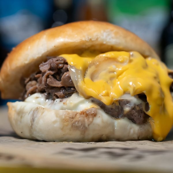 A Mojo's cheesesteak with melted cheese, steak, and white sauce on a bun.