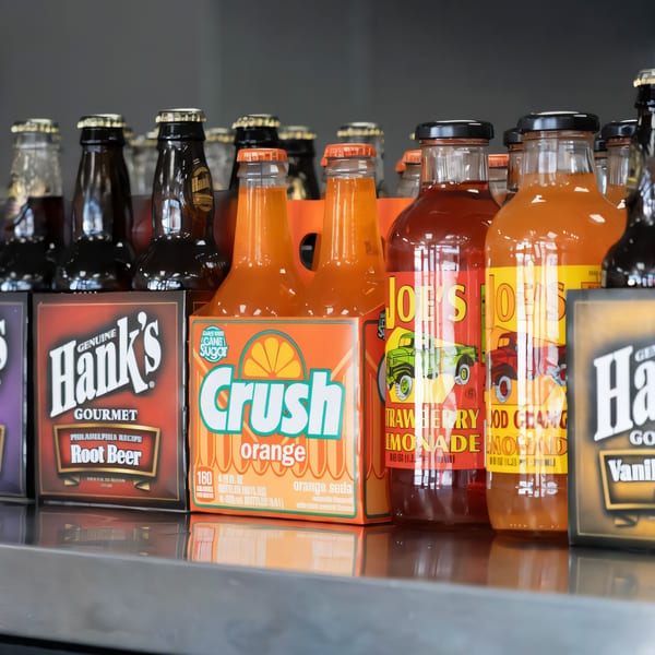 Assorted bottled sodas, including Hank's Root Beer, Crush Orange, and Mojo's Strawberry Lemonade.