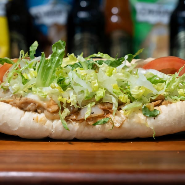 Mojo's cheesesteak with melted cheese, grilled onions, lettuce, and tomatoes on a hoagie roll.