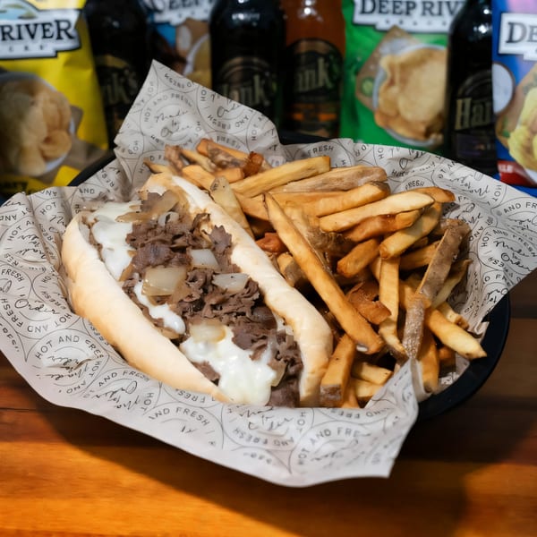 Mojo's cheesesteak with melted cheese and onions, served with fries in a basket.
